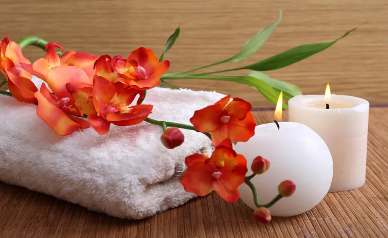 Spa towels, candles and orchid flowers arranged on bamboo